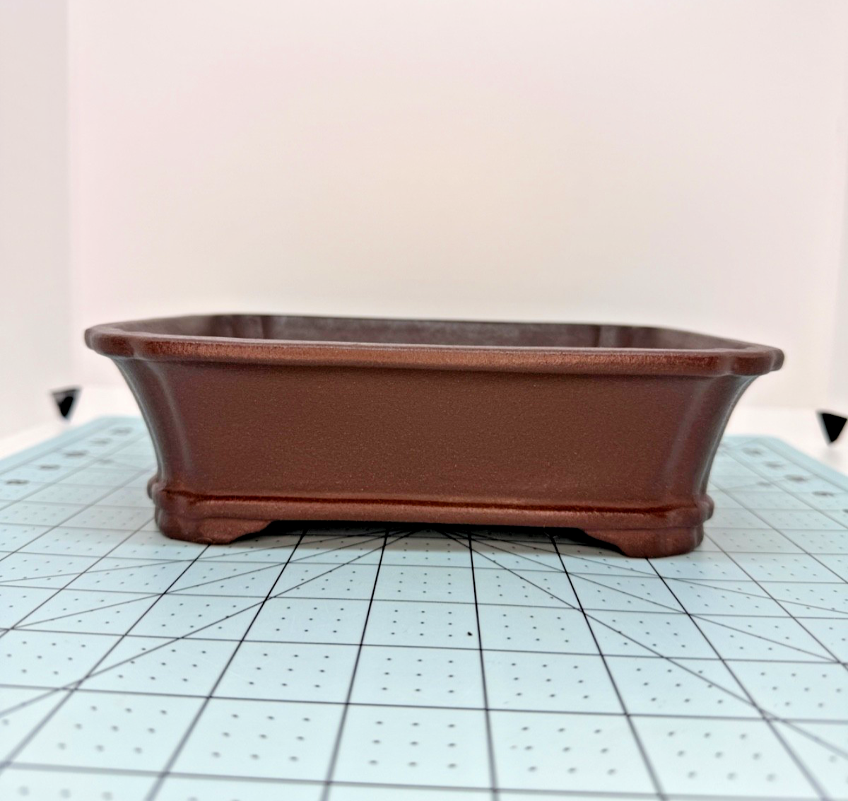 Long-side view of the brown rectangular pot with banded base and shaped feet