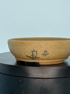 Close side view of the ochre oval pot with small boat motifs