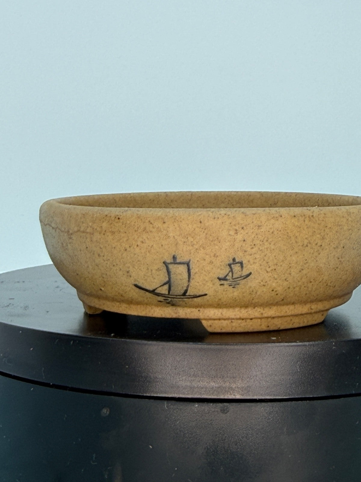 Close side view of the ochre oval pot with small boat motifs