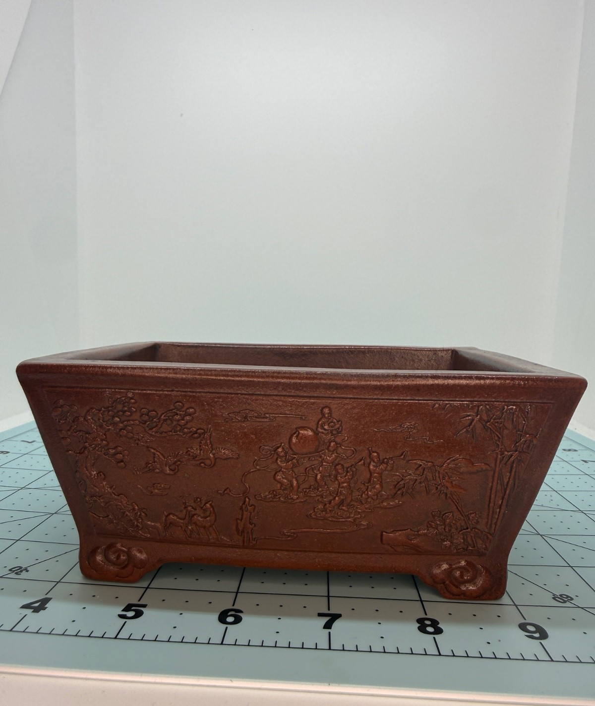 Long-side view of the rectangular pot with landscape relief on a measuring mat