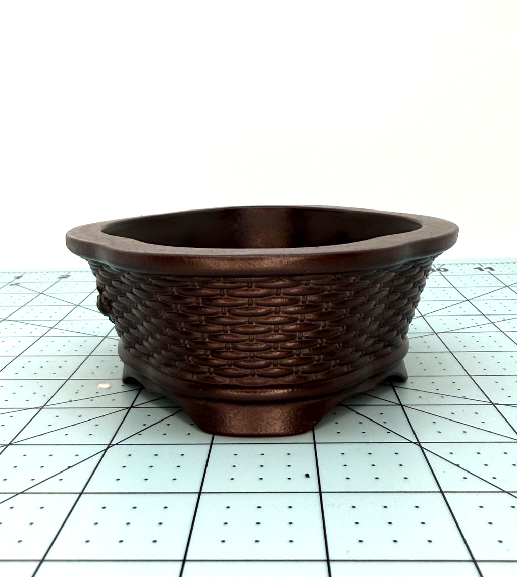 Angled end view of the brown oval pot's woven texture and low feet