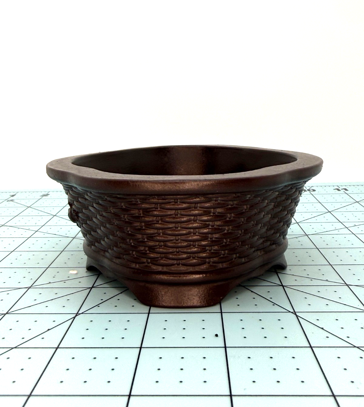 Angled end view of the brown oval pot's woven texture and low feet