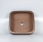 Interior of a rounded square brown pot with central drainage hole