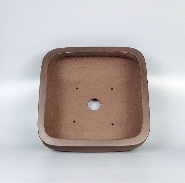 Interior of a rounded square brown pot with central drainage hole