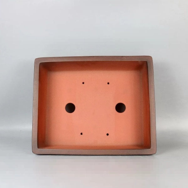 Top view of rectangular orange-brown pot showing two large and four small holes