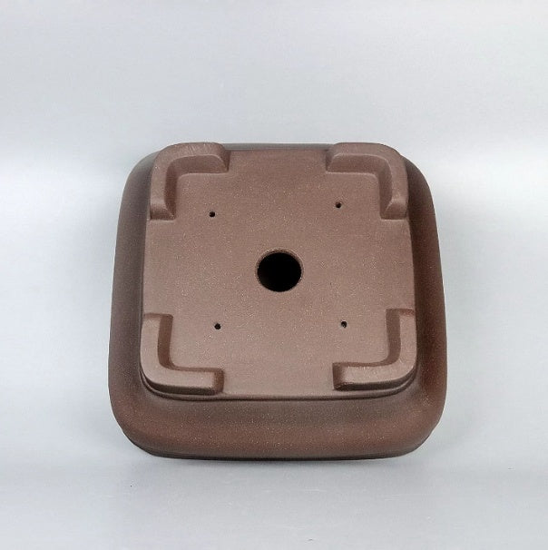 Underside of the brown square pot with central drainage and small holes