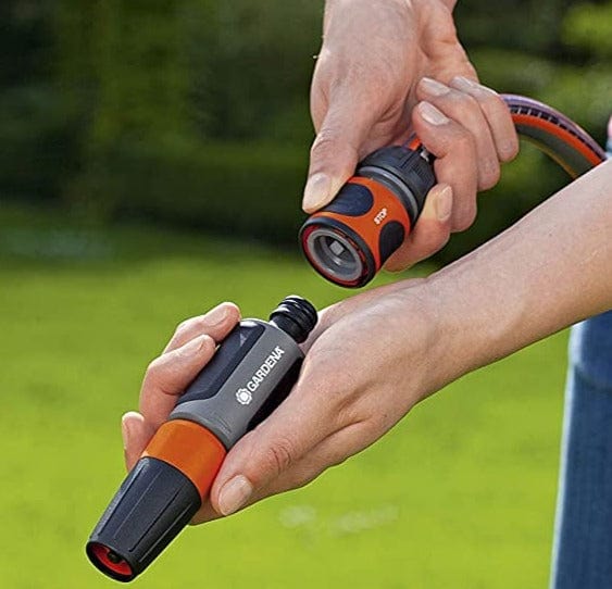 Hands connecting an orange and gray hose connector to a GARDENA spray nozzle