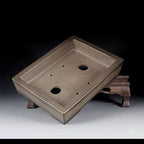 Angled interior of taupe rectangular pot showing drainage openings