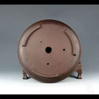 Underside of the brown round pot showing drainage openings
