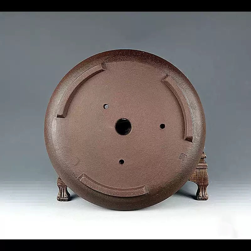 Underside of the brown round pot showing drainage openings