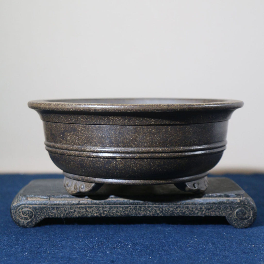 Dark metallic-toned round pot with horizontal bands and decorative feet