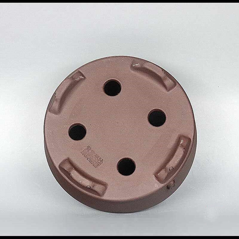 Round clay pot underside with four drainage openings