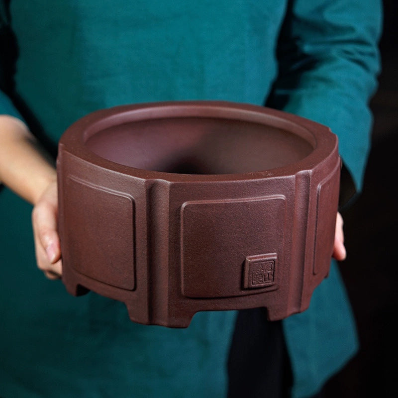 Deep brown hexagonal Zisha bonsai pot, held to show scale