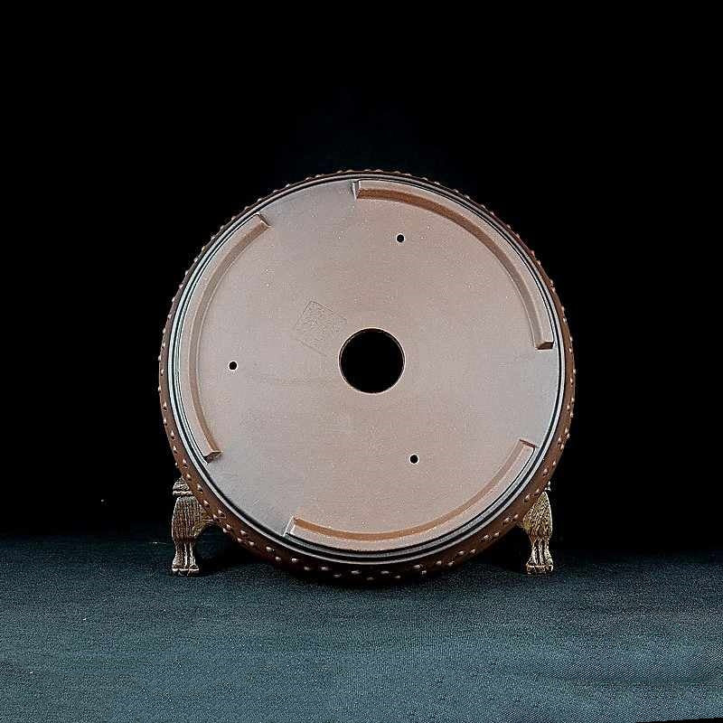Underside of the round pot showing central drainage opening and small holes
