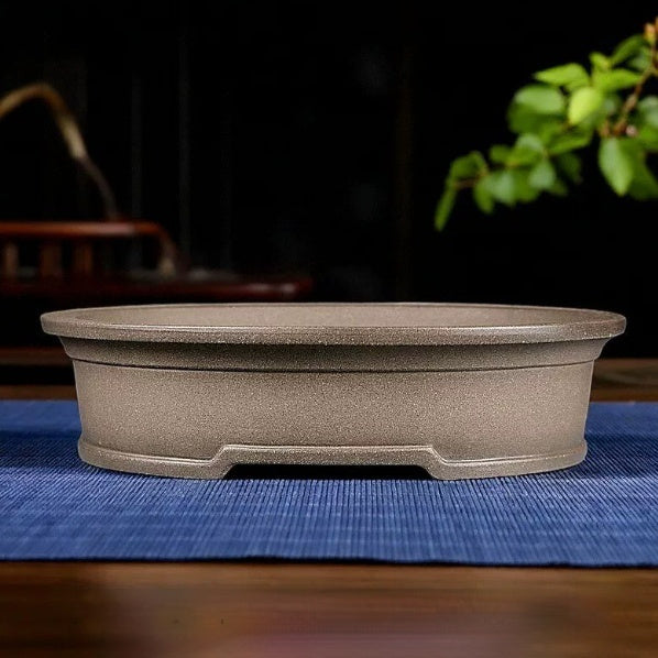 Taupe oval bonsai pot with a broad rim and notched base