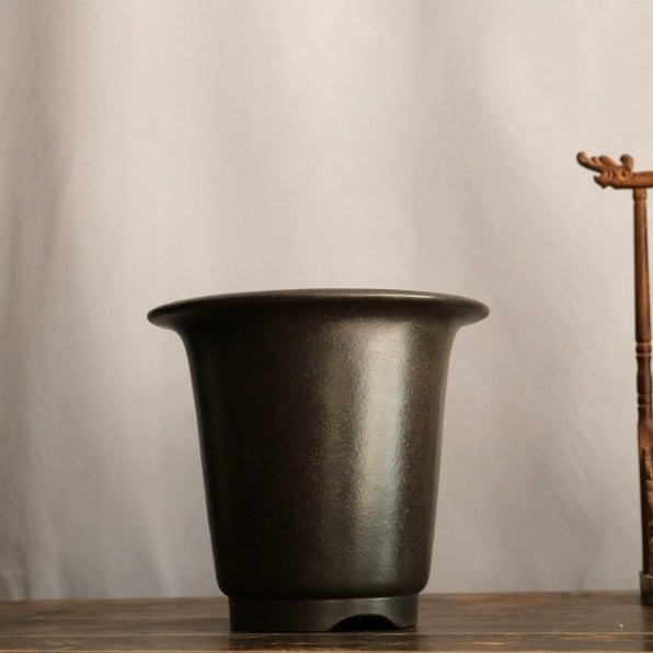 Front view of dark tapered round bonsai pot on a wooden table