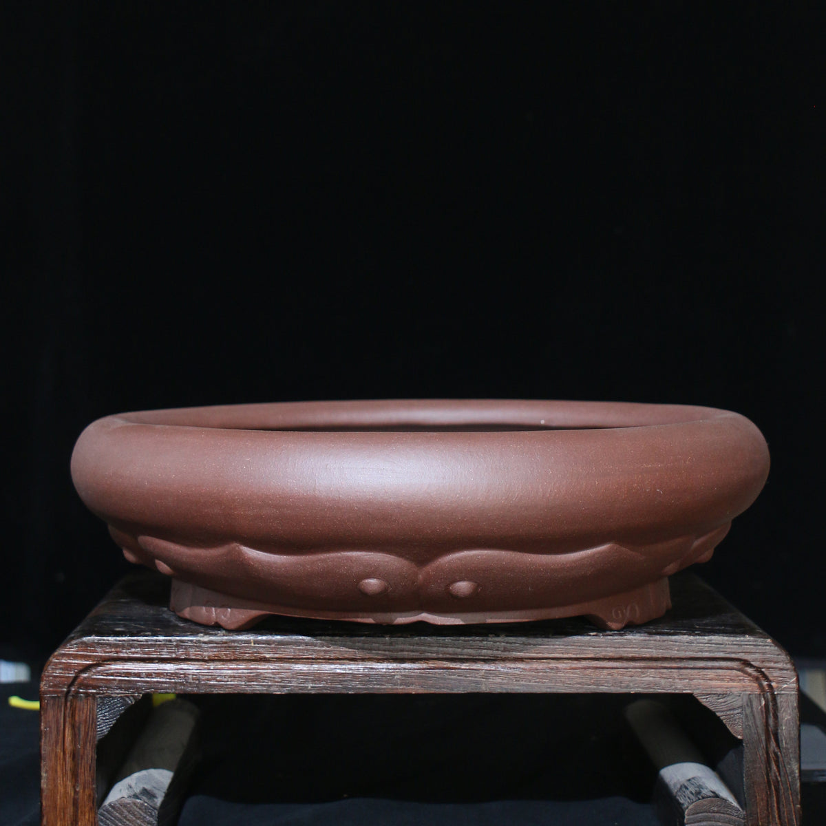 Angled brown round pot showing petal decoration and sculpted feet