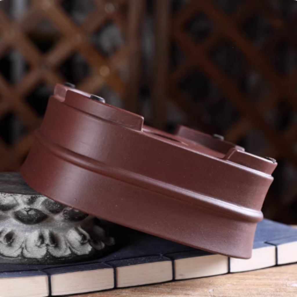 Upside-down brown rounded square pot tilted on stone showing feet