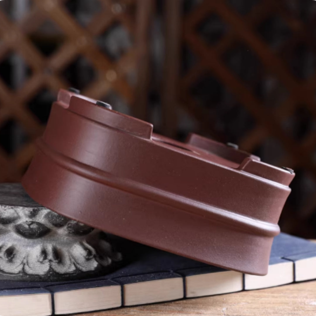 Upside-down brown rounded square pot tilted on stone showing feet