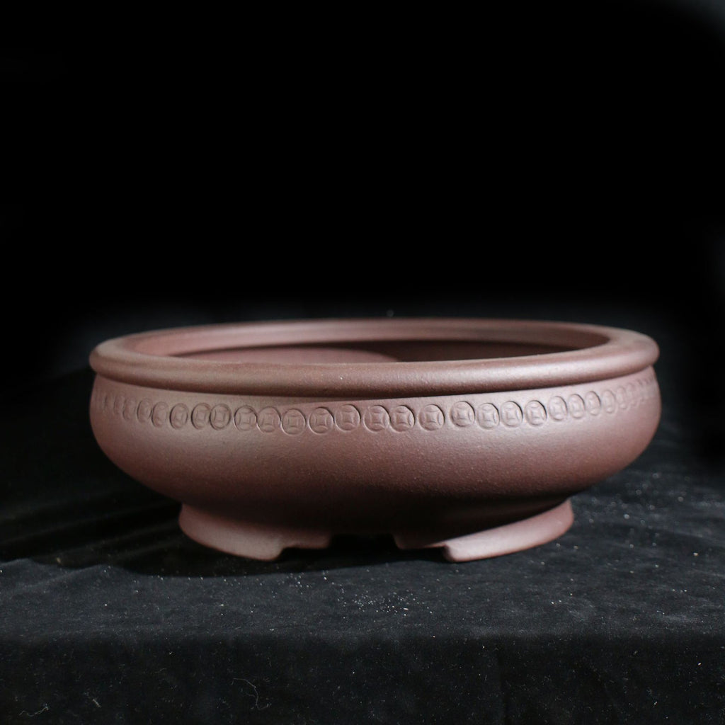 Reddish-brown round pot with repeated coin-like motifs below the rim