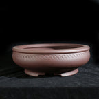 Reddish-brown round pot with repeated coin-like motifs below the rim