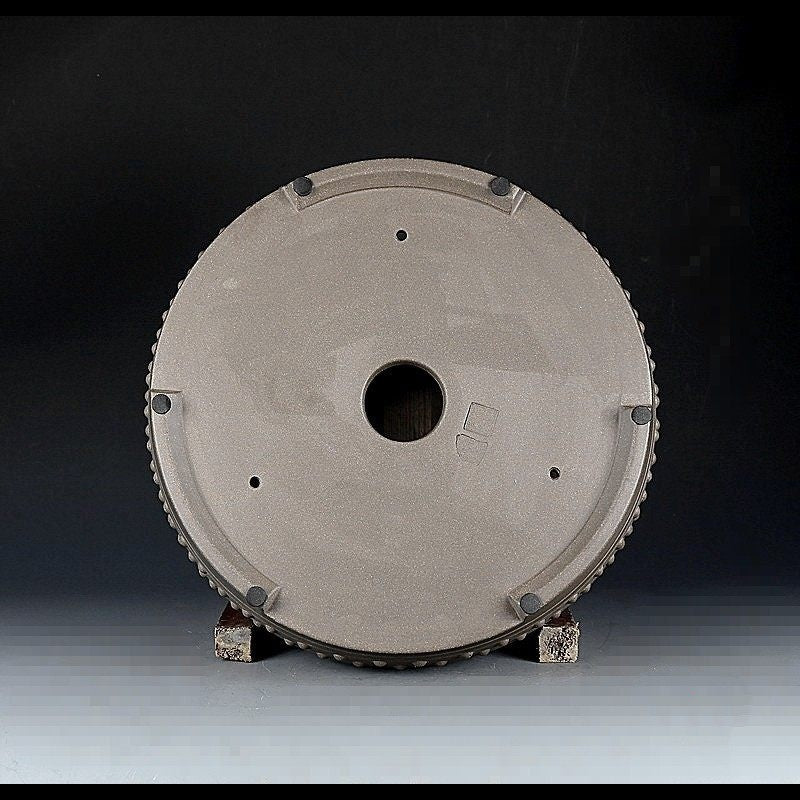 Underside of the taupe round pot showing feet and drainage openings