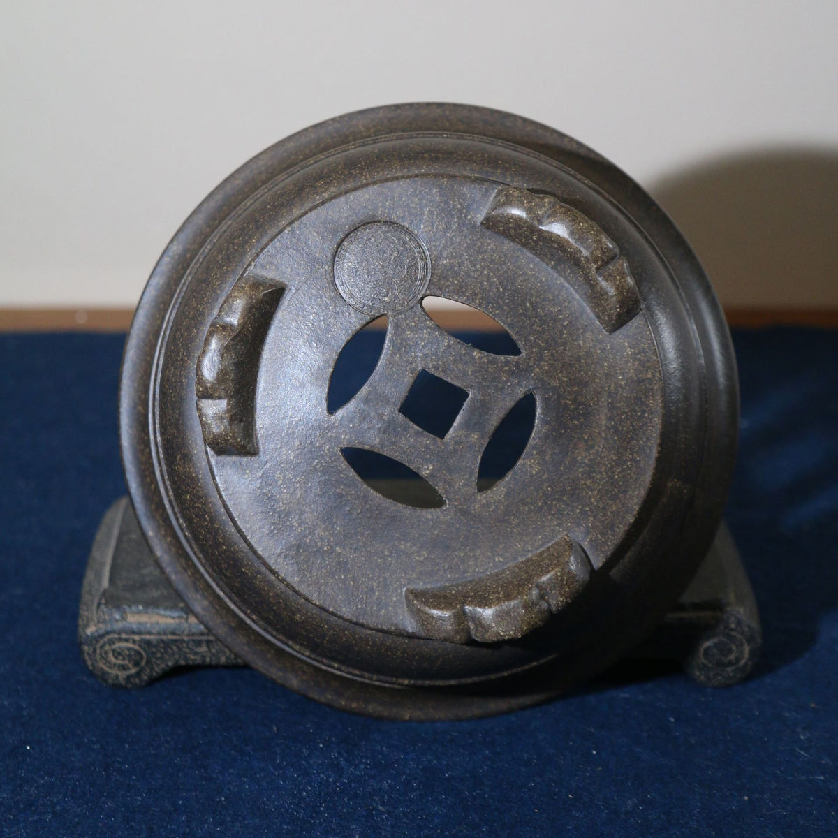 Underside of the dark round pot showing decorative feet and drainage pattern
