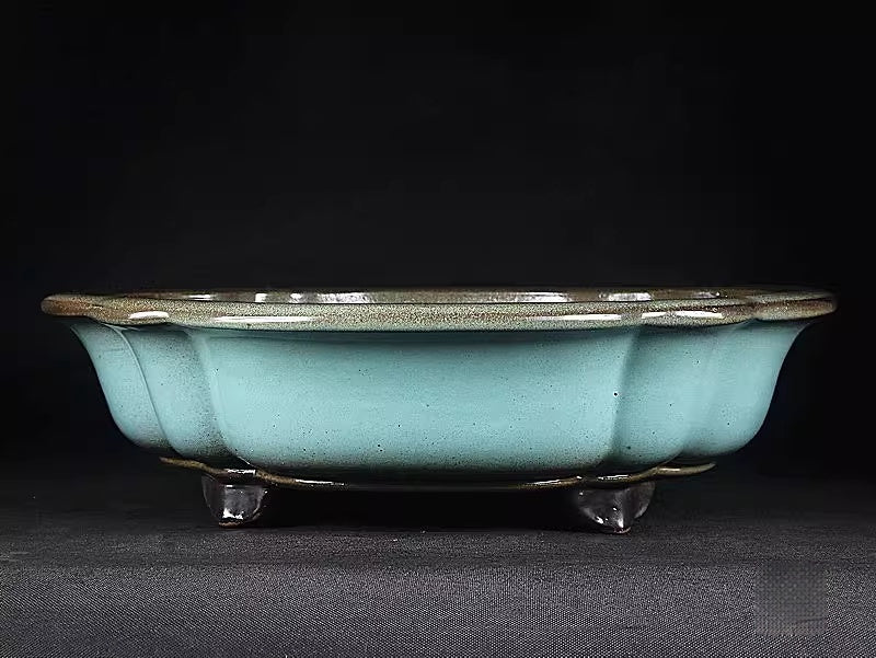 Scalloped rim and dark feet of light-green mokko pot