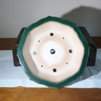 Underside of the green pot showing pale clay and multiple drainage openings