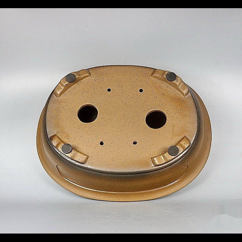 Underside of ochre oval pot showing two large openings and corner feet