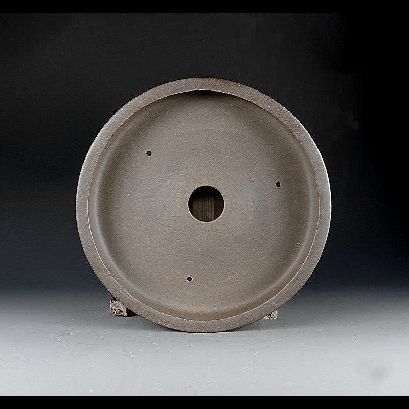 Interior of the taupe round pot with central drainage opening and three smaller holes