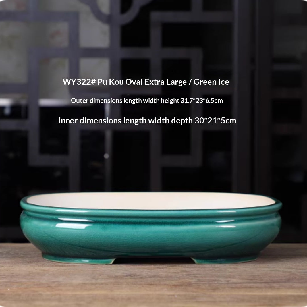 Deep green oval bonsai pot with a double rim and pale interior, with measurements above