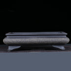 Front view of the dark speckled pot showing its raised rim and flared feet