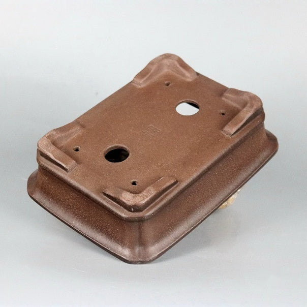 Underside angle of the brown pot showing feet and drainage openings