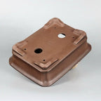 Underside angle of the brown pot showing feet and drainage openings