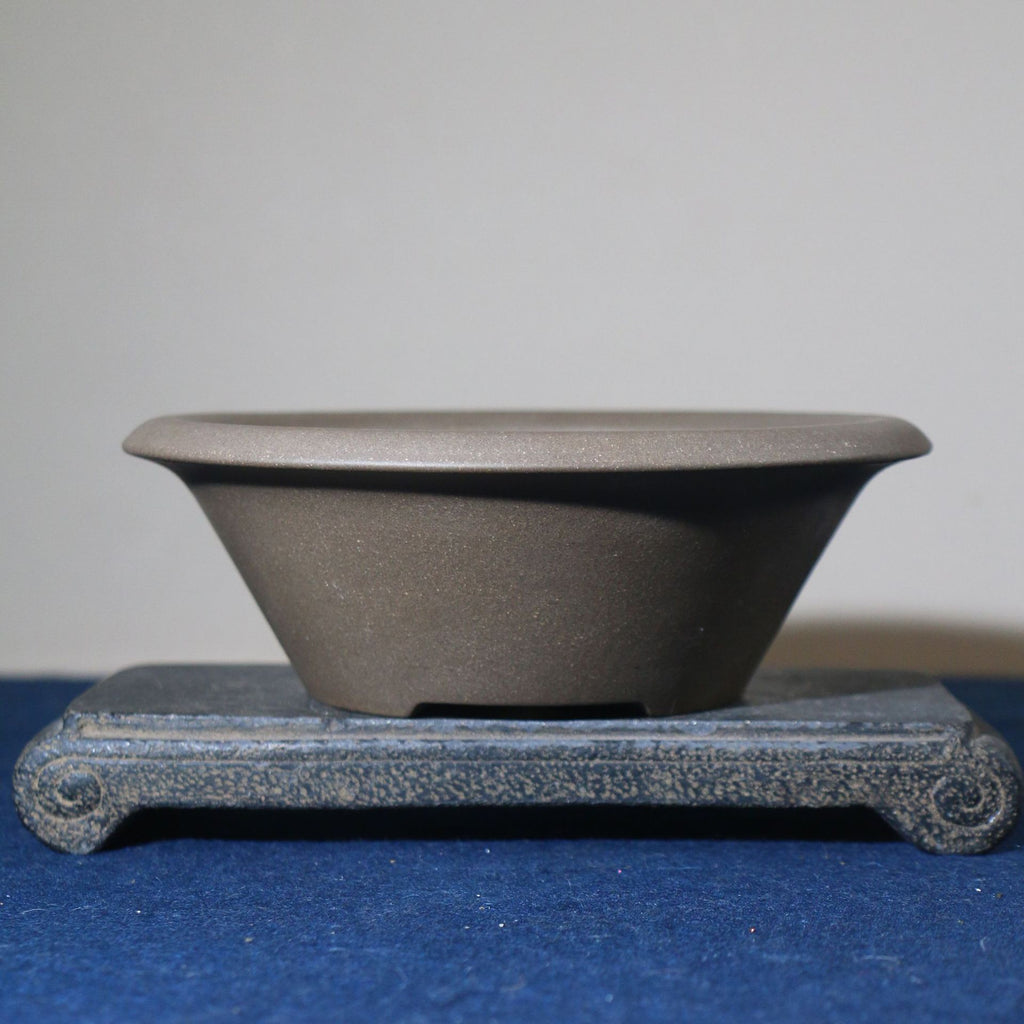 Gray round conical bonsai pot with broad flared rim on a stone stand