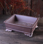 Angled purple-brown rectangular pot showing open interior and curled feet