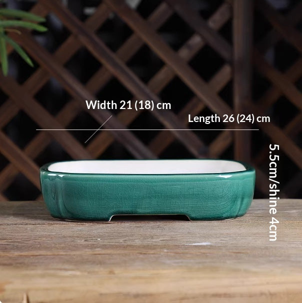 Green oval bonsai pot with a pale interior, low feet and measurement labels