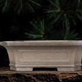 Taupe rectangular pot with flared sides, recessed panels and broad feet