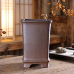 Tall brown square bonsai pot with raised rim and arched openings between feet
