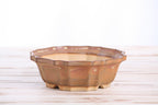 Angled view of the warm tan-brown flower-shaped bonsai pot showing its rim and side profile