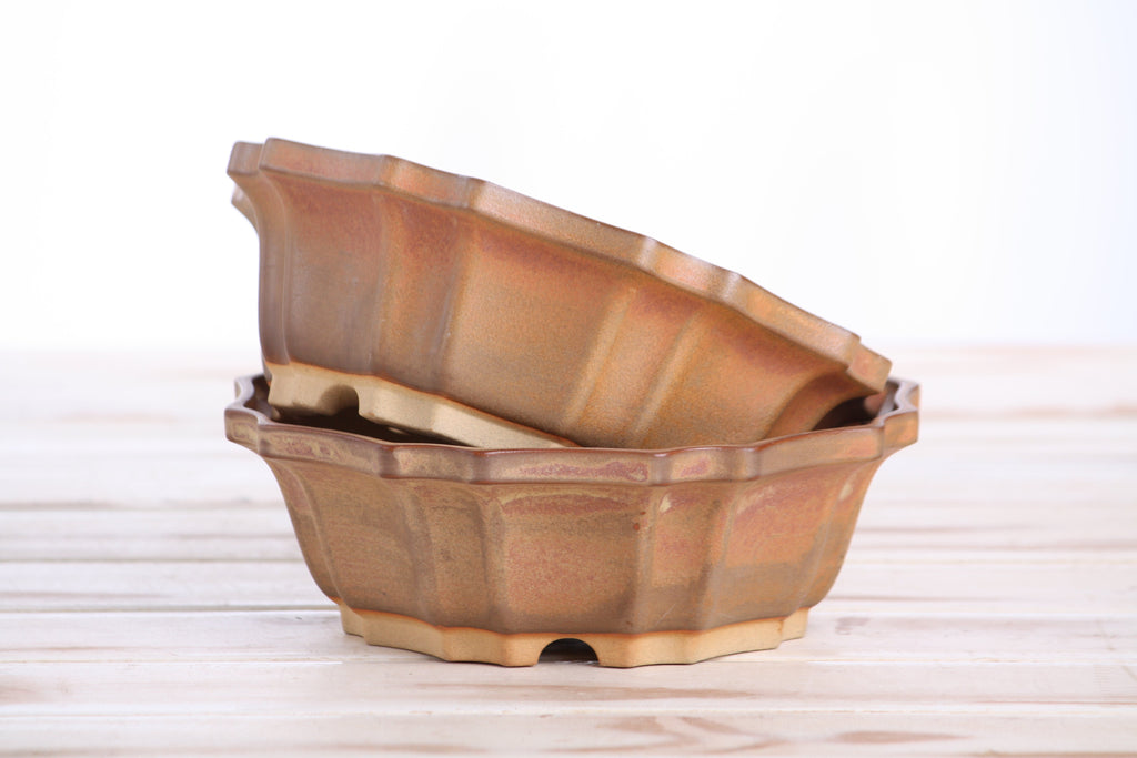 Two matching warm tan-brown pots stacked at an angle to show their profiles