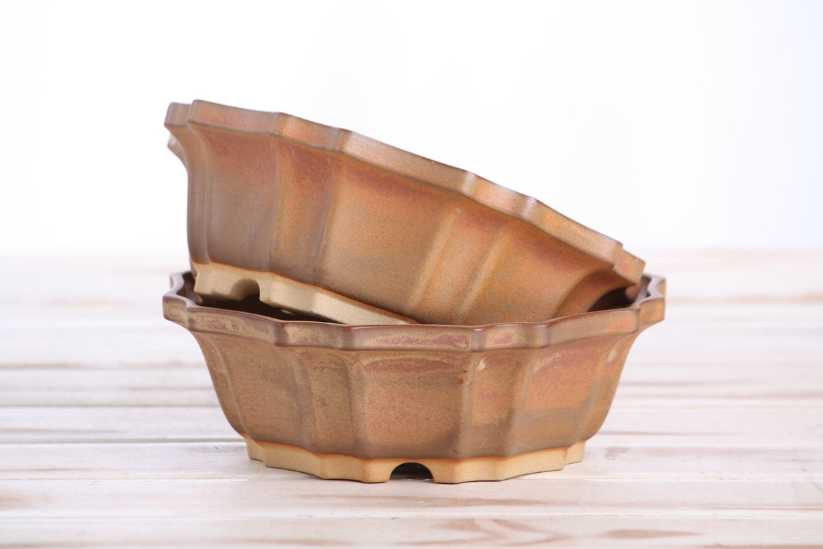 Two matching warm tan-brown pots stacked at an angle to show their profiles