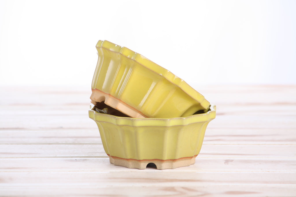 Two matching yellow pots stacked at an angle to show their profiles