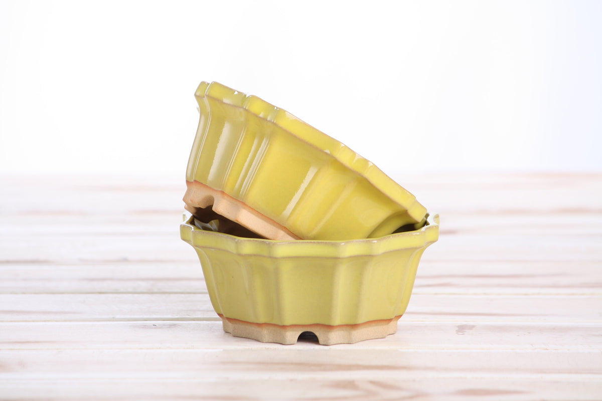 Two matching yellow pots stacked at an angle to show their profiles