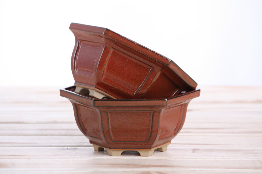 Two matching rust-red pots stacked at an angle to show their profiles