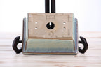 Underside of the pale blue rectangular bonsai pot showing a central drainage hole, smaller openings and impressed maker's marks