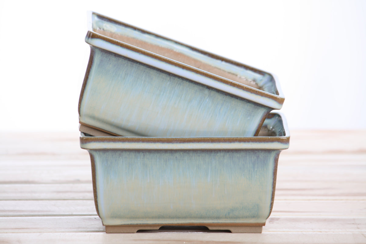 Two matching pale blue pots stacked at an angle to show their profiles