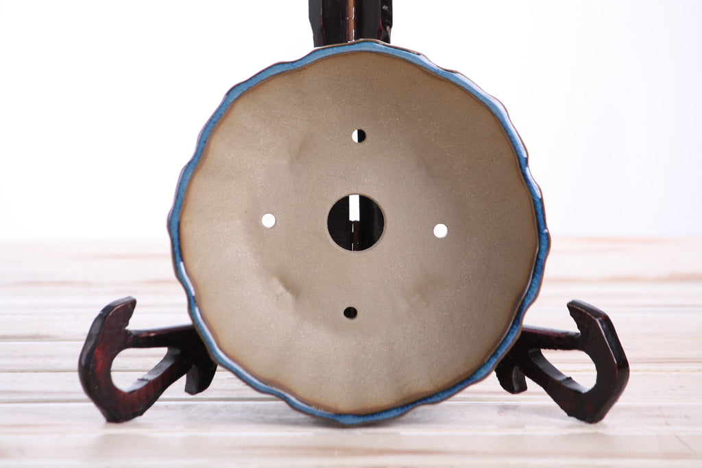 Interior of the blue-green round fluted bonsai pot showing a central drainage hole and four smaller openings