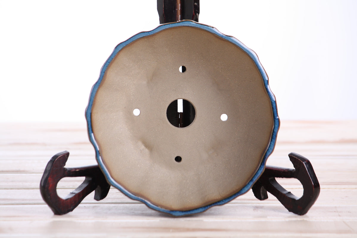 Interior of the blue-green round fluted bonsai pot showing a central drainage hole and four smaller openings